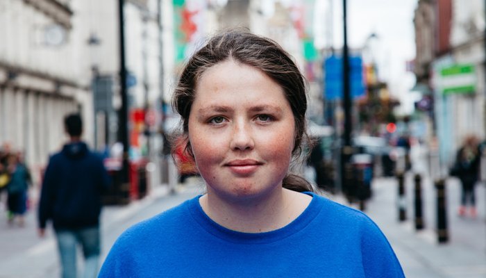 Portrait of Angharad in blue t-shirt standing in the middle of a high street