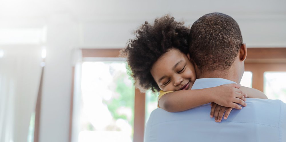 Portrait of father and son hugging laughing in living room