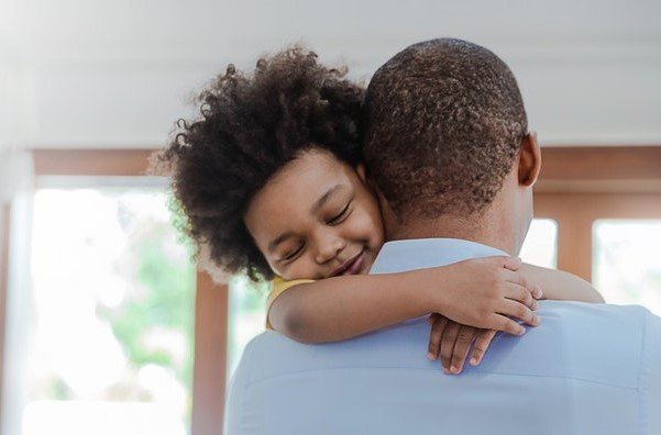 Father and son hugging in living room and smiling