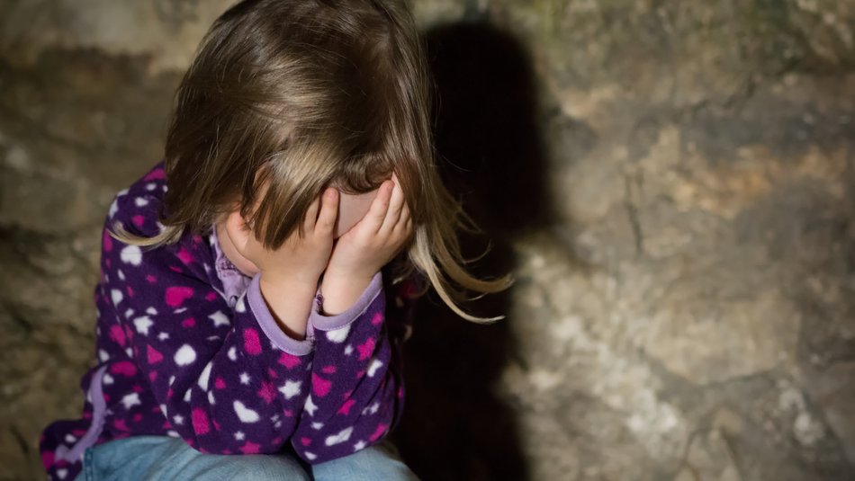 Sad young child covering face