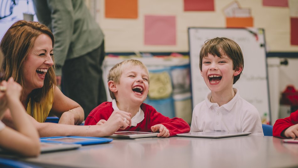 Students and teacher are laughing and enjoying themselves during a digital tablet lesson at school