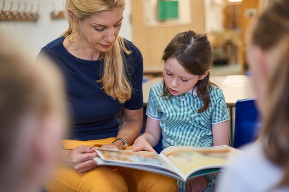 Teacher reading to young girl
