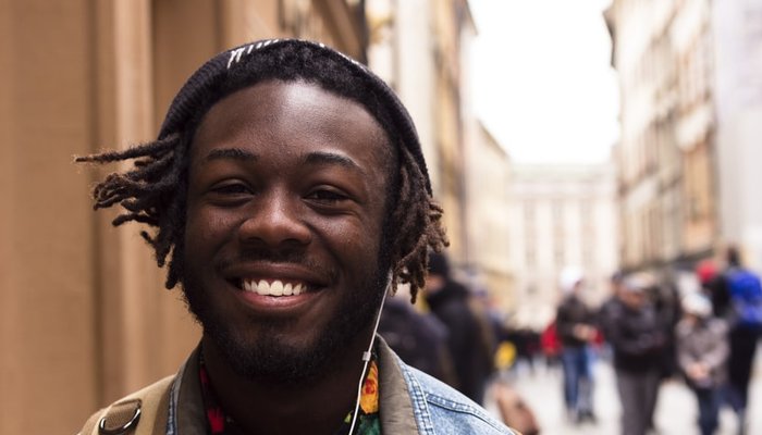 Teenage boy wearing headphones walking down crowded city street