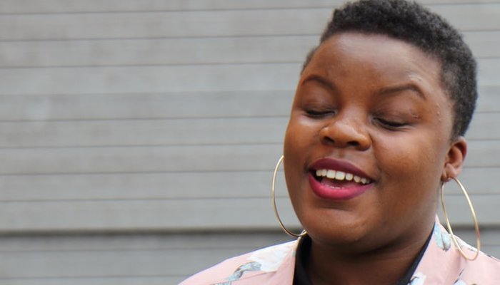 Teenage girl wearing floral jacket standing in front of wall