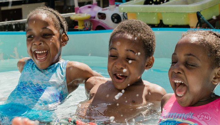 Three young children splashing in a baby pool