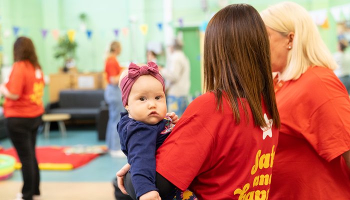 Toddler being held by an Action for Children staff member, looking at the camera