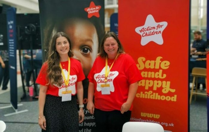 Two Action for Children workers standing in front of two large Action for Children banners