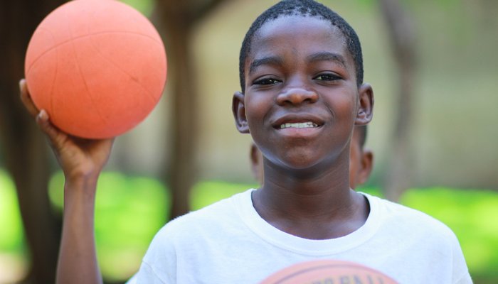 Young boy smiling and holding basketball in park
