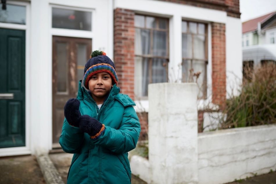 Young boy wearing coat and gloves outside