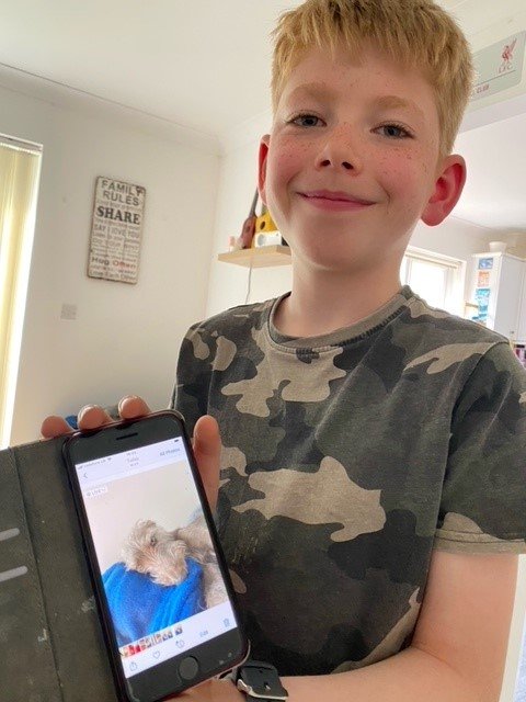 Young Carer Caiden showing a picture of his dog on his phone screen to the camera