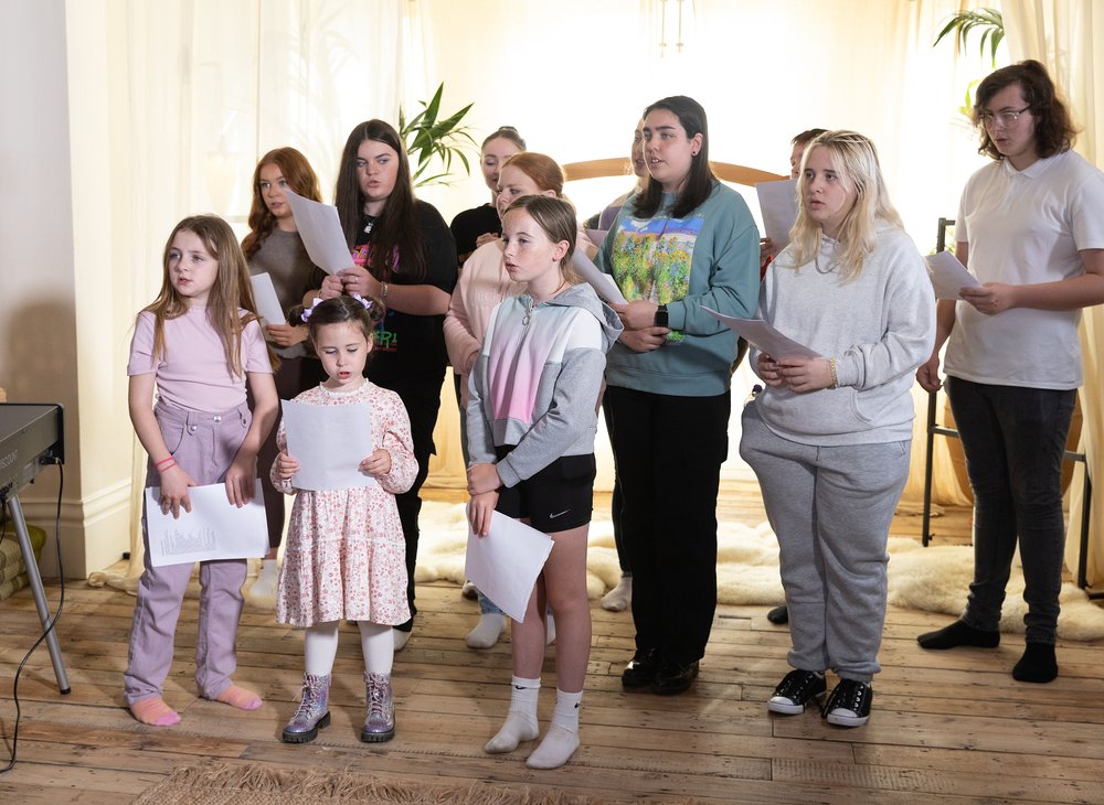 Young carers aloud choir singing in a house