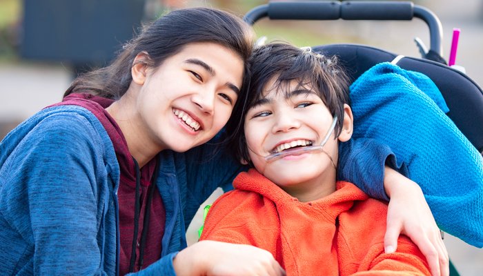 Happy young boy in a wheelchair posing with his sister