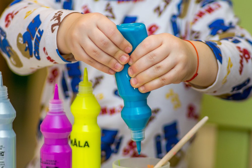 young child squeezing paint bottle.jpg
