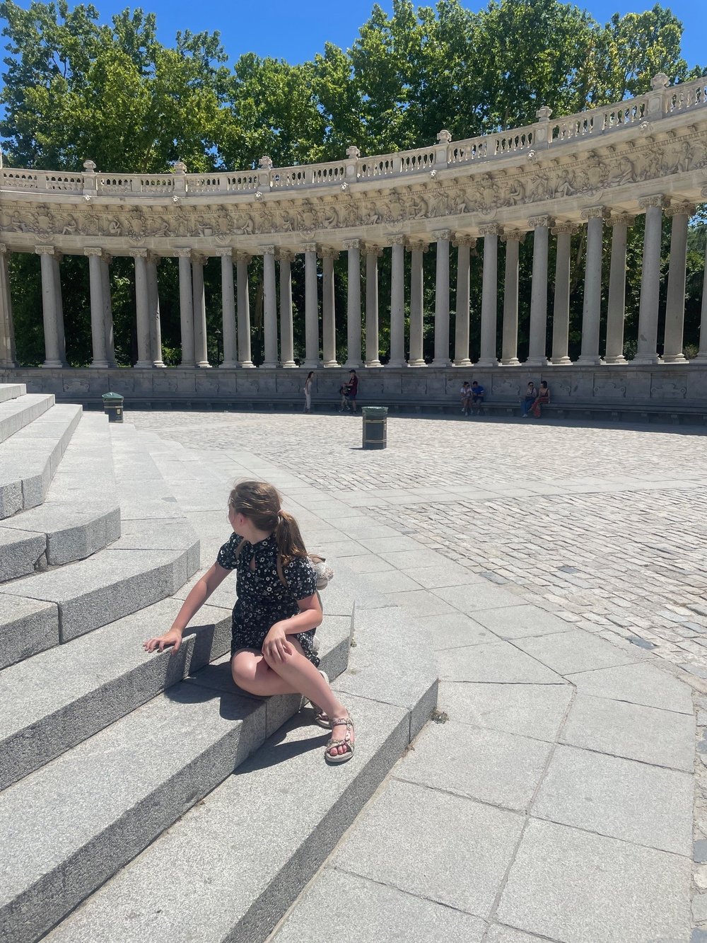 Young foster child sitting in plaza looking away from camera