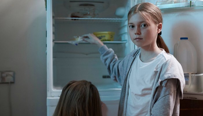 Young girl looking in empty fridge with sister