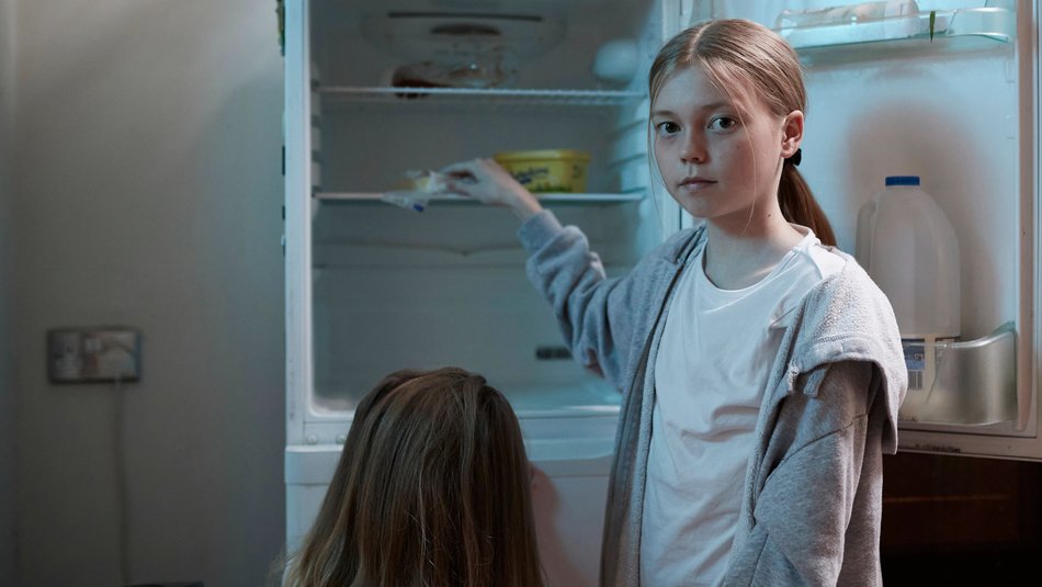 Young girl looking in empty fridge with sister