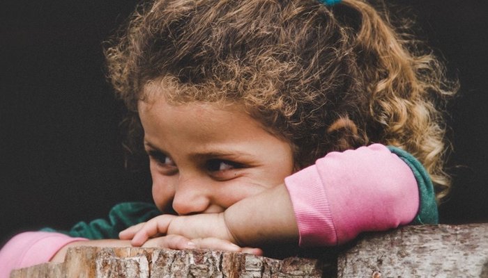 Young girl resting on tree trunk and smiling