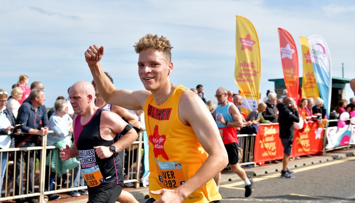 Young man smiling at camera in an Action for Children vest running the Great North Run 2022
