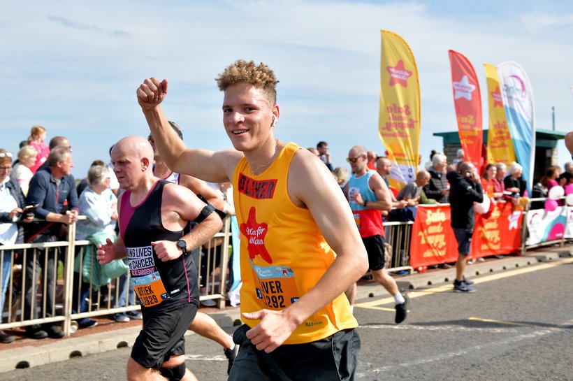 Young man smiling at camera in an Action for Children vest running the Great North Run 2022