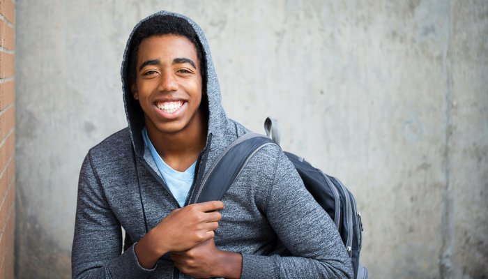 Young teenage boy with big smile wearing backpack and hoodie.jpg