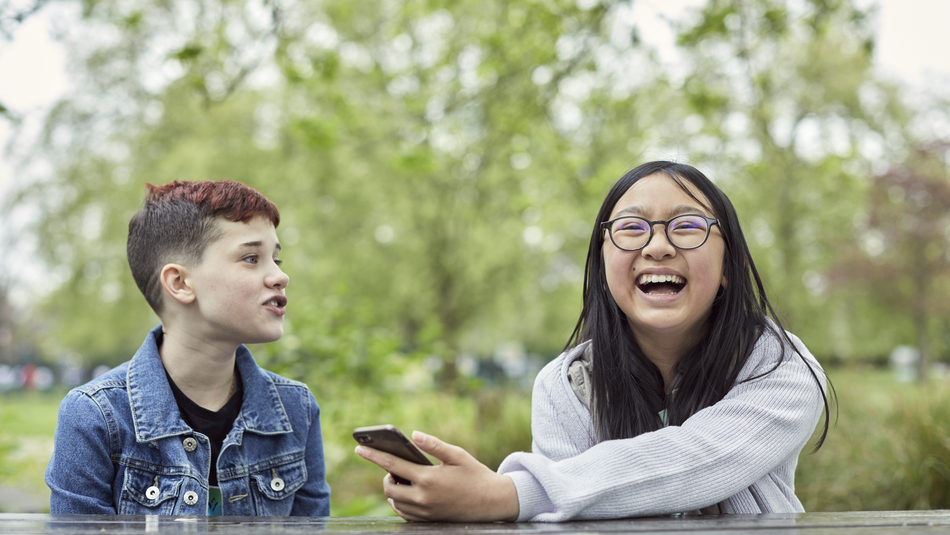 Image of two young people laughing in a park