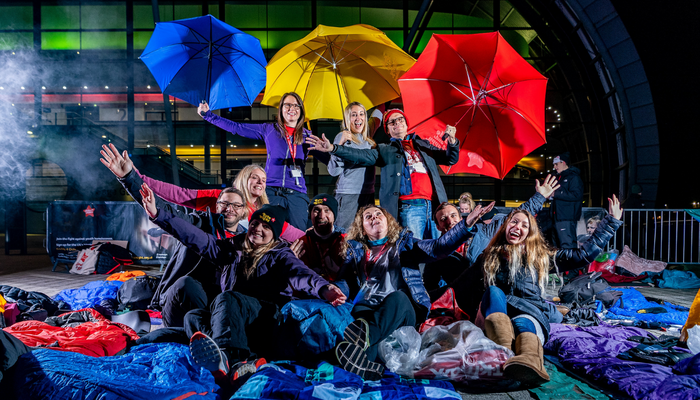 Group of people at Byte Night event. They are outside, Smiling and laughing and are surrounded by sleeping bags and umbrellas