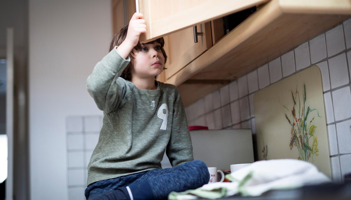 young boy looking in cupboard.png